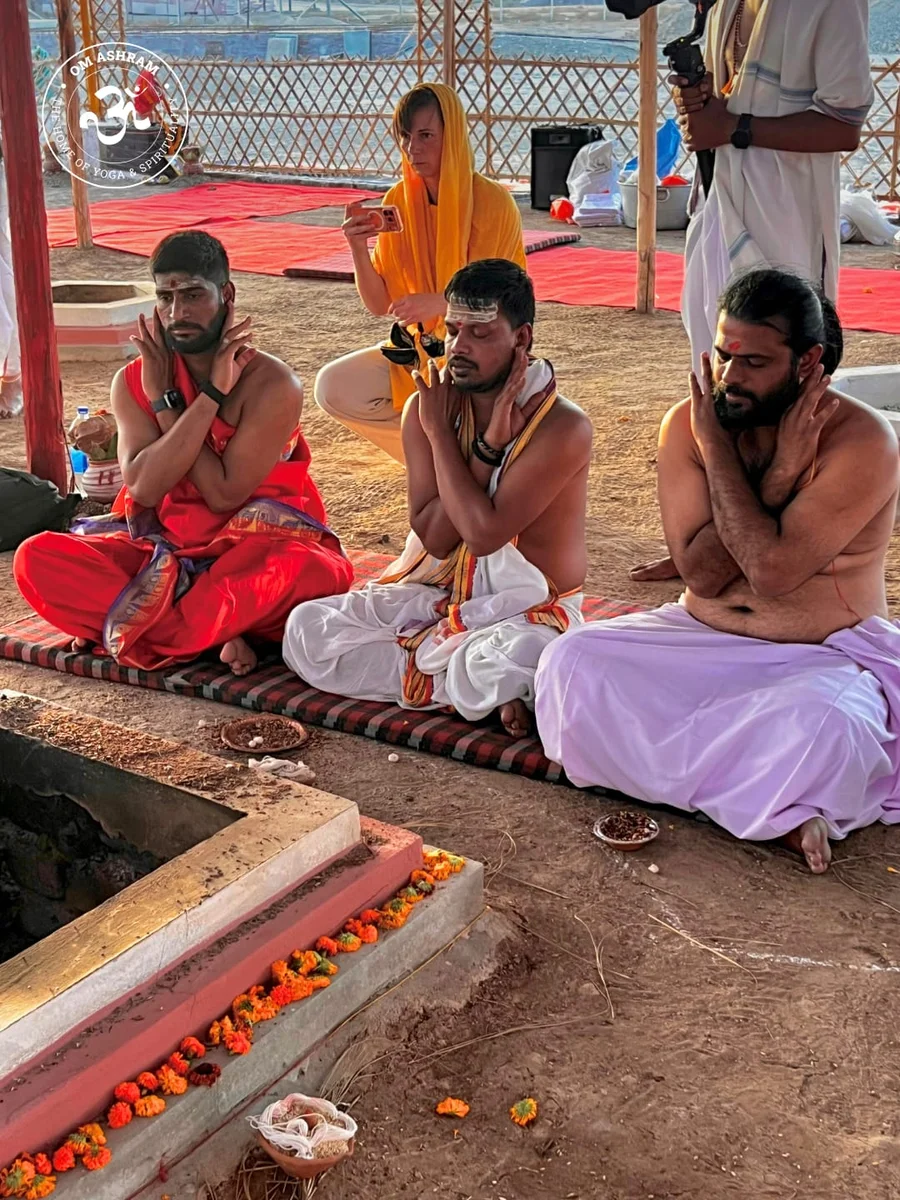 Men sitting at the fire ceremony with traditional arm gestures.